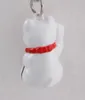 A close-up shot of a white lucky cat keychain with a red collar. Produktbild-Vorschau