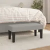 A light gray upholstered bench with black legs is placed in front of a bed with striped bedding. Náhled obrázku produktu