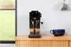 An espresso machine is shown on a wooden counter, with two cups of espresso being brewed. Voir les images du produit