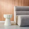 A striped side table next to a textured sofa. Produktbild-Vorschau