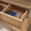 A close-up view of an open wooden drawer with a blue notebook and a gold binder clip inside. Produktbild-Vorschau