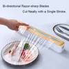 A hand is shown using a plastic wrap dispenser to cover a plate of food. The dispenser has a wooden accent and a blue cutting strip. A fork and knife are visible in the background. Produktbild-Vorschau