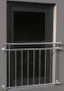 A silver metal balcony railing in front of a dark window. Podgląd zdjęcia produktu