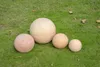 Four terracotta garden balls of varying sizes are placed on a green lawn. Produktbild-Vorschau