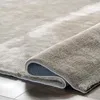 A close-up view of a beige rug, showing its texture and the way it is rolled up. Produktbild-Vorschau