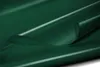 A close-up, abstract shot of a dark green, glossy material, likely PVC tarpaulin, with a section folded over, creating curves and highlights. Anteprima dell’immagine prodotto