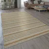 A rug is placed on a wooden floor in a living room setting, with a sofa and coffee table in the background. Produktbild-Vorschau