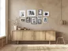 A collection of framed pictures displayed above a wooden sideboard in a room with neutral-toned walls and flooring. Náhled obrázku produktu
