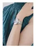 A close-up shot of a woman's wrist wearing a silver Guess watch. Náhled obrázku produktu