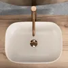 A top-down view of a beige speckled basin with a gold faucet, set on a wooden countertop. Anteprima dell’immagine prodotto