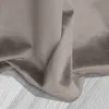 A close-up view of beige velour fabric, showing its texture and folds, resting on a light wooden surface. Podgląd zdjęcia produktu