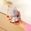 A hand holding a cute gray cat-shaped stress toy. Voir les images du produit