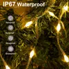 Close-up of warm white LED string lights on a green, possibly artificial, Christmas tree, with water droplets on the lights and branches. Produktbild-Vorschau