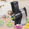 A kitchen counter with a vegetable slicer in use, slicing cucumbers and onions. Produktbild-Vorschau