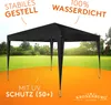 A black pop-up gazebo is set up in a grassy outdoor area with an orange foreground. Produktbild-Vorschau