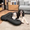 A dog is lying on a black dog bed in a living room. Produktbild-Vorschau