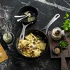 A close-up overhead shot of ravioli being prepared in a pan, with various ingredients and cooking utensils arranged around it on a dark, speckled countertop. Náhľad obrázku produktu