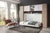 A bedroom with a murphy bed and storage units, featuring a chair and large windows. Produktbild-Vorschau