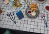 A table setting with food and cutlery, including a blue silicone cutlery holder. Produktbild-Vorschau