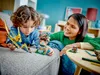 A mother and child are playing with LEGOs on a couch. Náhled obrázku produktu