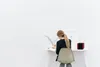 A person is sitting at a desk and writing, with a small red heater on the desk. Produktbild-Vorschau