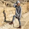 A woman is posing on stone steps in an outdoor, rocky environment. Voir les images du produit