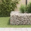 Two gabion cubes filled with stones are placed on a lawn in a garden setting, with lush green foliage and a wooden fence in the background. Podgląd zdjęcia produktu