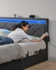 A young woman lies on a bed, reaching for her phone. The bed has a grey upholstered headboard with blue LED lighting, and storage drawers underneath. A camera and a small potted plant are on a shelf above the headboard. Náhled obrázku produktu