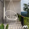 A white macrame hanging chair on a balcony with a scenic view. Náhled obrázku produktu