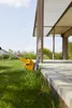 A grass trimmer is being used to trim the edge of a lawn next to a paved patio and a modern outdoor structure. Produktbild-Vorschau