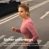 A woman is running on a street while wearing headphones. Produktbild-Vorschau