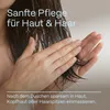 A person applying a product to their hair and hands. Produktbild-Vorschau