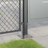 Close-up of a metal post base and chain-link fence section on a concrete surface with grass in the foreground. Produktbild-Vorschau