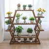 A wooden plant stand with multiple tiers filled with various potted plants, placed indoors near a window with sheer curtains. Anteprima dell’immagine prodotto