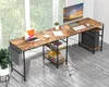 A spacious L-shaped desk with a rustic wood finish and black metal legs, set up in a bright room with a large window in the background. Anteprima dell’immagine prodotto