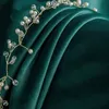 A close-up of a beaded garland on a draped green fabric. Produktbild-Vorschau
