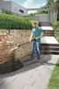 A man is using a pressure washer to clean a stone wall in an outdoor setting with stairs and greenery. Produktbild-Vorschau