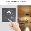 A hand is shown interacting with a digital thermostat mounted on a wall, with a living room scene in the background. Náhled obrázku produktu