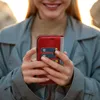 A person holding a red flip phone case with cards inserted. Produktbild-Vorschau
