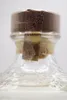 A close-up shot of the top of a glass bottle, showing the cork and a tamper-evident seal. Produktbild-Vorschau