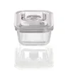 A square glass food storage container with a clear lid and a gray locking mechanism, shown in isolation against a white background with its reflection. Produktbild-Vorschau