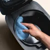 A hand is cleaning the inside of a rice cooker with a blue cloth. Produktbild-Vorschau