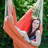 A woman relaxing in an orange hammock chair outdoors. Podgląd zdjęcia produktu