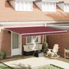 A burgundy awning extends over a patio area with outdoor furniture, a rocking chair, and potted plants. Produktbild-Vorschau