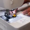 Close-up shot of a person's hands using a sewing machine. Produktbild-Vorschau