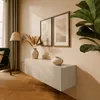 A modern living room scene with a wall-mounted TV lowboard, artwork, and a floor lamp. Náhľad obrázku produktu