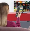 A woman is sitting on a couch, holding a remote control and looking at a TV screen displaying a grid of movie posters. Voir les images du produit