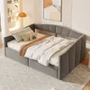 A gray upholstered daybed with bedding and pillows in a room with shelves and artwork. Produktbild-Vorschau