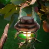 A solar-powered lantern hanging from a tree branch with apples in the background. Produktbild-Vorschau
