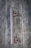 A metal handle rests on a wooden surface. Produktbild-Vorschau